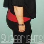 Busty Mature Kendall standing indoors in a red top and black pants